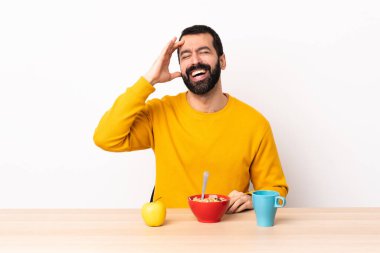 Kafkasyalı bir adam bir masada kahvaltı ederken çok gülümsüyor..