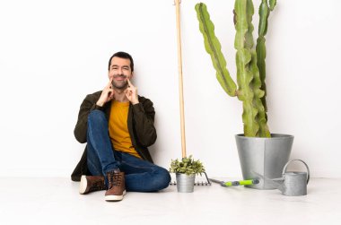 Bahçıvan içeride yerde oturmuş mutlu ve hoş bir ifadeyle gülümsüyor.