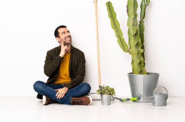 Bahçıvan içeride yerde oturuyor. Yukarı bakarken bir fikir düşünüyor.