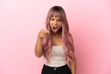 Pembe saçlı genç melez kadın pembe arka planda izole edilmiş hayal kırıklığına uğramış ve ön tarafı işaret ediyor.