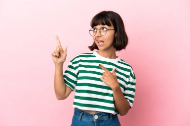 Pembe arka planda izole edilmiş genç melez kadın işaret parmağıyla işaret etmek harika bir fikir.