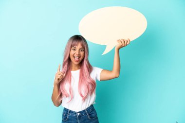 Mavi arka planda izole edilmiş pembe saçlı melez bir kadın elinde şaşırmış bir ifadeyle boş bir konuşma balonu tutuyor.