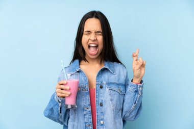 Çilekli milkshake ile izole edilmiş mavi arka planı olan genç bir kadın.