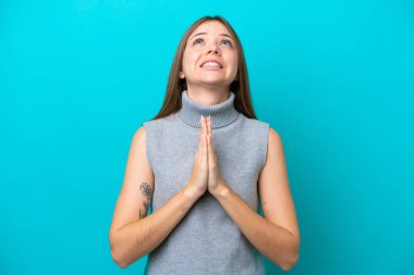 Mavi arka planda izole edilmiş genç Litvanyalı kadın avuç içlerini bir arada tutuyor. İnsan bir şey ister.