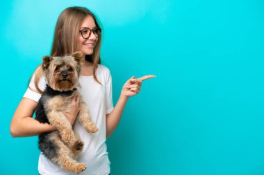 Genç Litvanyalı bir kadın mavi arka planda izole edilmiş bir köpek tutuyor.