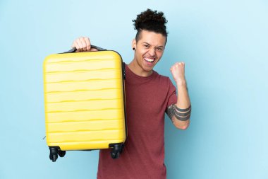 İzole edilmiş mavi geçmişi olan beyaz bir adam seyahat çantasıyla tatilde.
