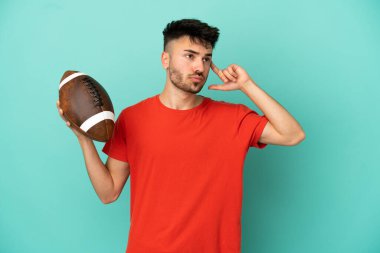 Rugby oynayan beyaz bir adam mavi arka planda izole edilmiş. Şüpheleri ve düşünceleri var.