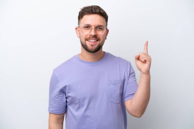 Beyaz arka planda izole edilmiş genç beyaz bir adam en iyinin işareti olarak parmağını kaldırıyor.
