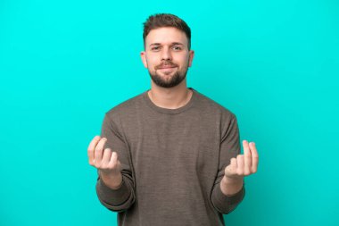 Mavi arka planda izole genç beyaz adam para jesti yapıyor