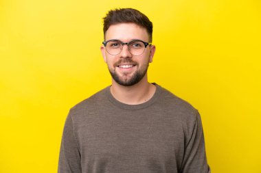 Sarı arka planda izole edilmiş, mutlu yüzlü, genç beyaz bir adam.