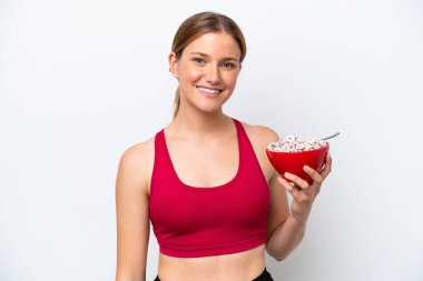 Genç, güzel sarışın kadın kahvaltı sütü içiyor. Beyaz arka planda izole edilmiş, gülümsüyor.