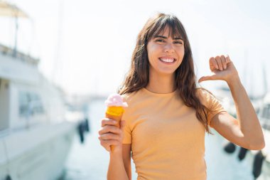 Kornet dondurması olan genç bir kadın açık havada gururlu ve kendini beğenmiş.