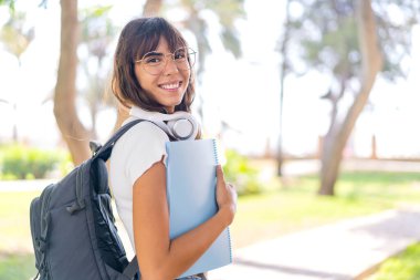 Dışarıda elinde bir defter tutan genç bir kadın.