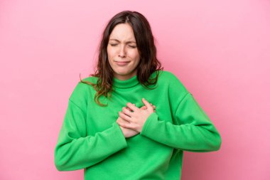 Pembe arka planda izole edilmiş, kalbinde ağrı olan beyaz bir kadın.