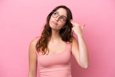 Genç beyaz kadın pembe arka planda izole edilmiş ve intihar jesti yapmada sorun yaşıyor.