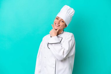Kafkasyalı genç aşçı kadın mavi arka planda izole edilmiş gülümsüyor.