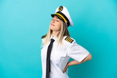 Uçak pilotu, mavi arka planda, çabaladığı için sırt ağrısından muzdarip.