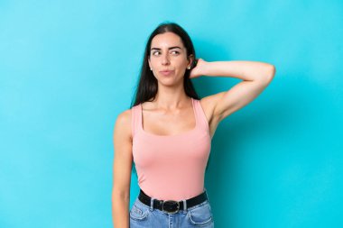 Kafkasyalı genç bir kadın mavi arka planda izole edilmiş. Şüpheleri var.