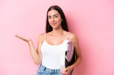 Pembe arka planda tartı makinesiyle izole edilmiş beyaz bir kadın.