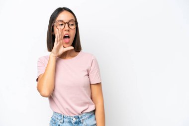 Beyaz arka planda izole edilmiş genç beyaz kadın yan tarafa bakarken sürpriz bir jest yaparak bir şeyler fısıldıyor.