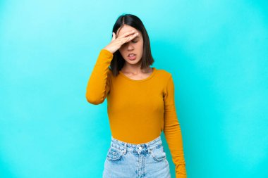 Kafkasyalı genç bir kadın mavi arka planda izole edilmiş, baş ağrısı var.