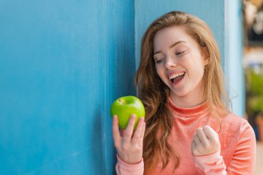 Açık havada elmalı genç kızıl kadın zaferi kutluyor.