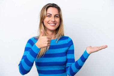 Beyaz arka planda izole edilmiş genç beyaz bir kadın bir ilan vermek ve onaylamak için avucunun içinde hayali bir mekan tutuyor.