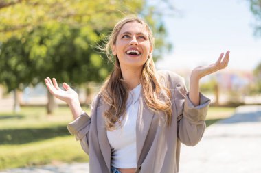 Genç, güzel sarışın Uruguaylı kadın açık havada gülümsüyor.