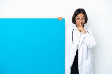 Beyaz arka planda izole edilmiş büyük bir pankartla genç melez doktor kadın parmağını ağzına koyan sessizlik işareti gösteriyor.