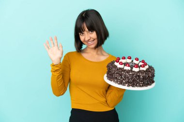 Genç melez kadın doğum günü pastasını tutarken mutlu bir ifadeyle selamlıyor.