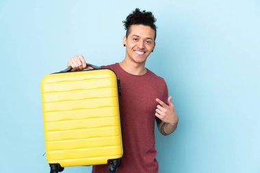 İzole edilmiş mavi geçmişi olan beyaz bir adam seyahat çantasıyla tatilde.