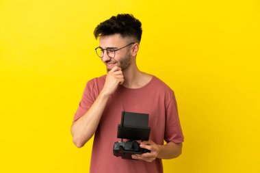 Uzaktan kumandayı elinde tutan adam sarı arka planda izole edilmiş bir şekilde yan tarafa bakıyor ve gülümsüyor.