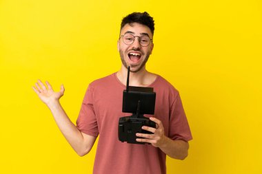 Dron uzaktan kumandalı adam sarı arka planda şok olmuş yüz ifadesiyle izole edilmiş.