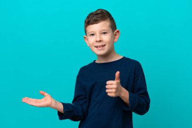 Küçük çocuk mavi arka planda izole edilmiş. Avucunun içinde hayali bir şey var. Bir ilan vermek için.