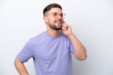 Beyaz arka planda izole edilmiş genç beyaz adam yukarı bakarken bir fikir düşünüyor.