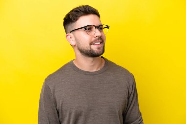 Sarı arka planda izole edilmiş, mutlu yüzlü, genç beyaz bir adam.