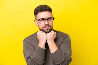Sarı arka planda gözlüklü ve yorgun genç beyaz bir adam.