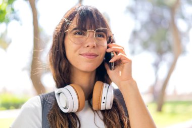 Açık havada cep telefonu kullanan genç bir kadın.