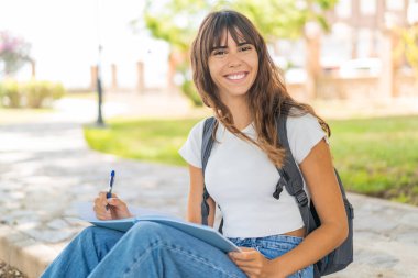 Dışarıda elinde bir defter tutan genç bir kadın.