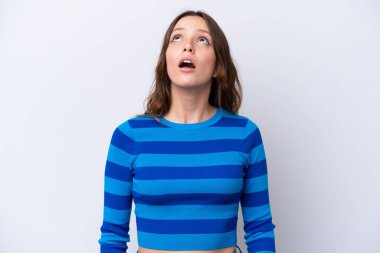 Beyaz arka planda izole edilmiş genç beyaz kadın yukarı bakıyor ve şaşırmış bir ifadeyle