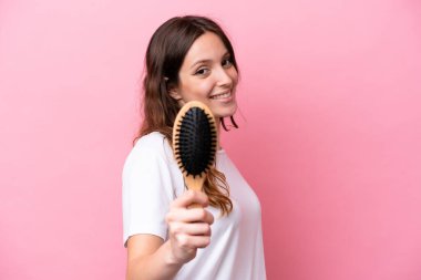 Pembe arka planda saçı taranmış, mutlu bir ifadeyle genç, beyaz bir kadın.