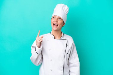 Kafkasyalı genç aşçı kadın mavi arka planda izole edilmiş ve şaşırmış.