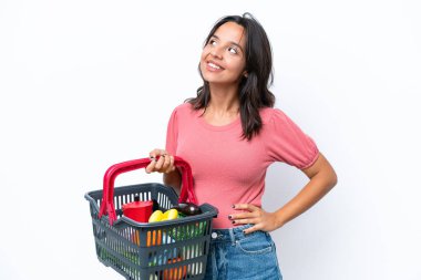 Elinde yiyecek dolu bir alışveriş sepeti tutan genç bir kadın yukarı bakarken bir fikir düşünüyor.