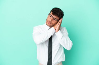 Kafkasyalı bir adam mavi arka planda izole edilmiş bir şekilde uyku jesti yapıyor.