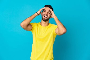 Kafkasyalı genç adam mavi arka planda tek başına gülüyor.