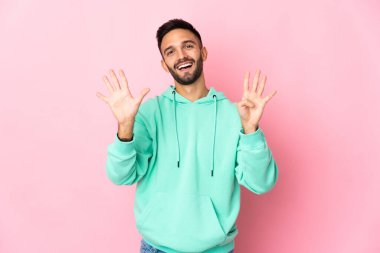 Young caucasian man isolated on pink background counting nine with fingers