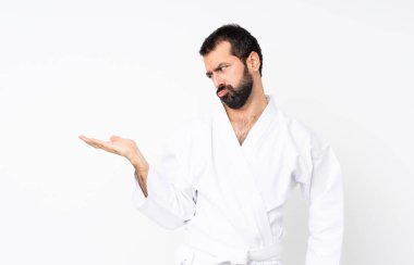 İzole edilmiş beyaz arkaplan üzerinde karate yapan genç adam, boşluğu şüpheyle dolduruyor