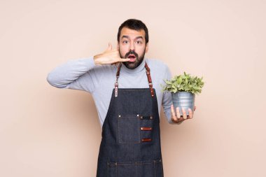 Bir bitkiyi izole edilmiş arka planda tutan bir adam telefon hareketinde bulunuyor.