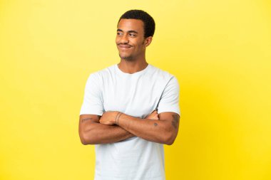 Sarı arka planda Afro-Amerikalı yakışıklı bir adam yan tarafa bakıyor.
