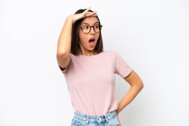 Beyaz arka planda izole edilmiş genç beyaz kadın yan tarafa bakarken sürpriz jest yapıyor.